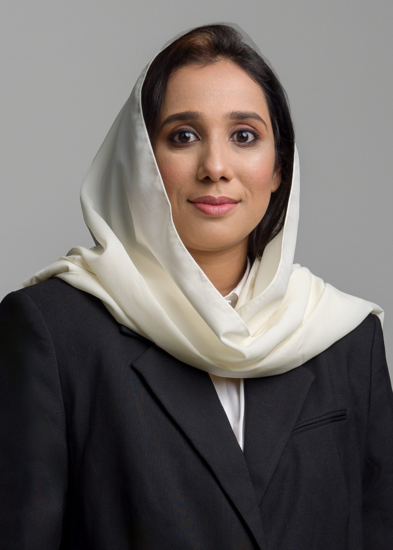 Professional headshot of a woman wearing a dark suit and light headscarf