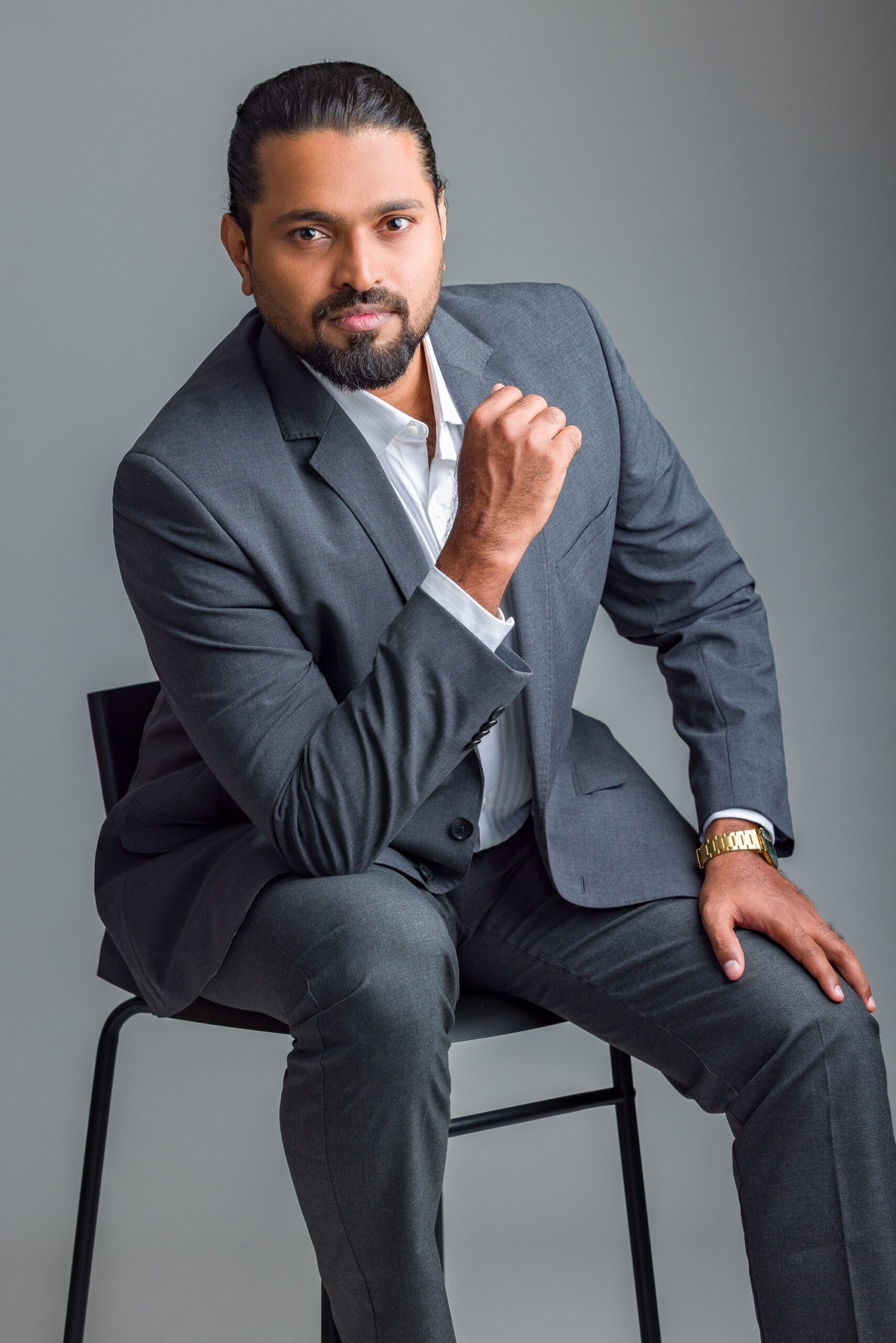 Seated studio portrait of a man in a grey suit