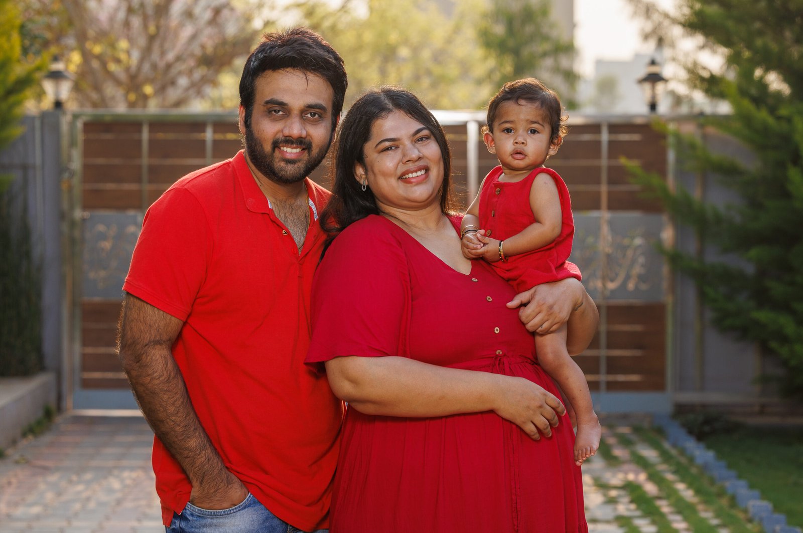 Parents holding their baby outdoors in matching red shirts