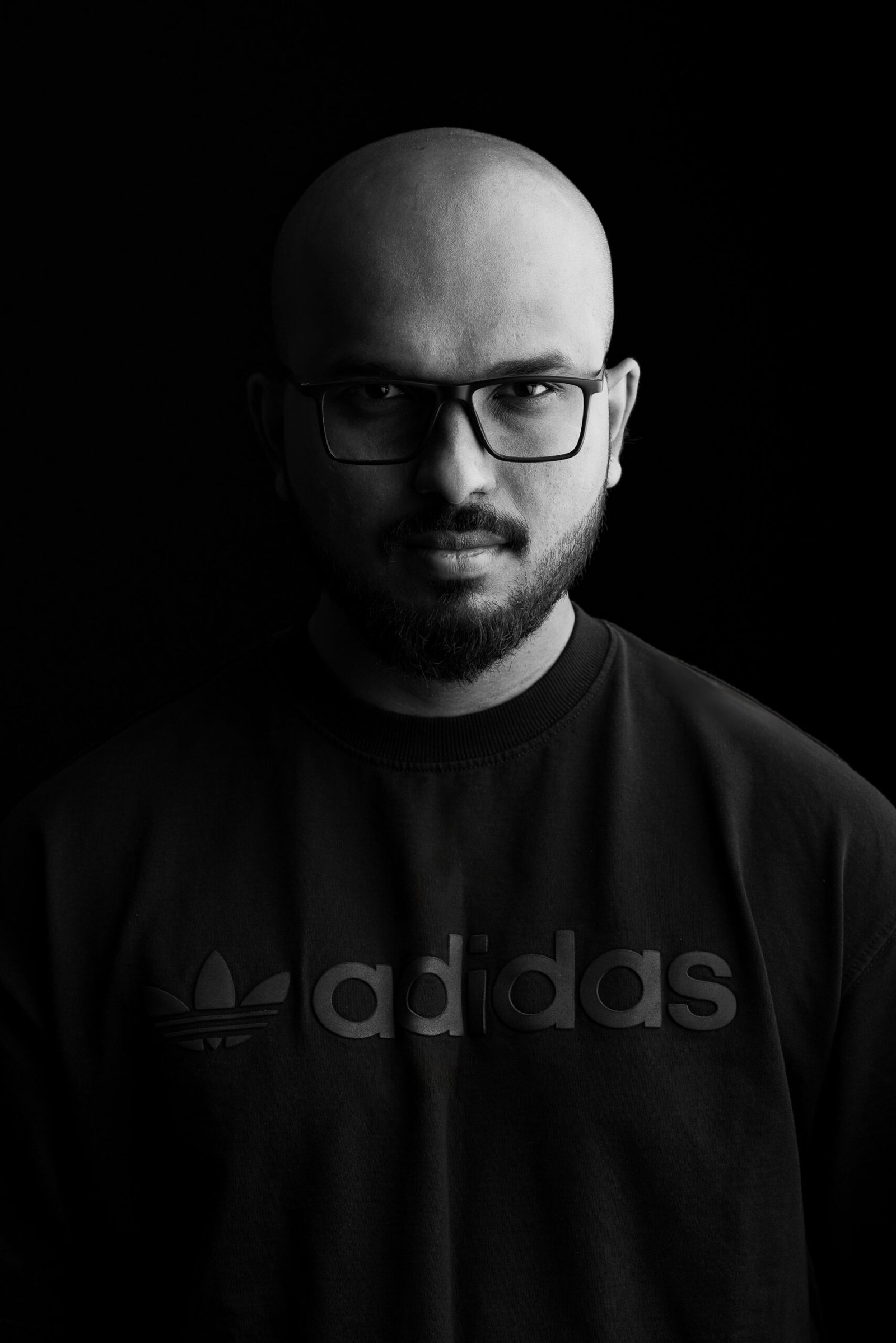 Black and white studio portrait of a man with glasses