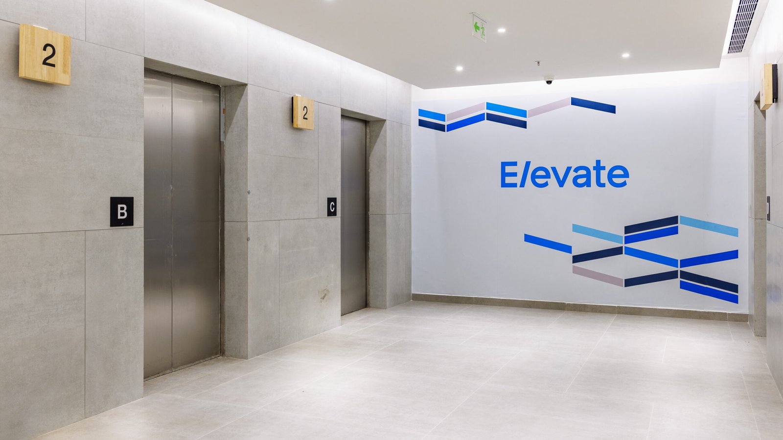 Modern commercial lift lobby with light stone walls and blue signage