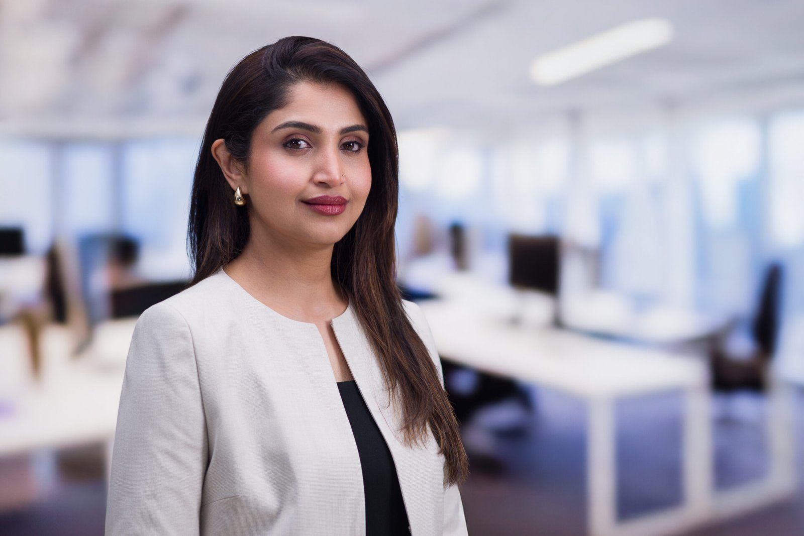 Corporate portrait of a woman in a light blazer against a softly blurred office background