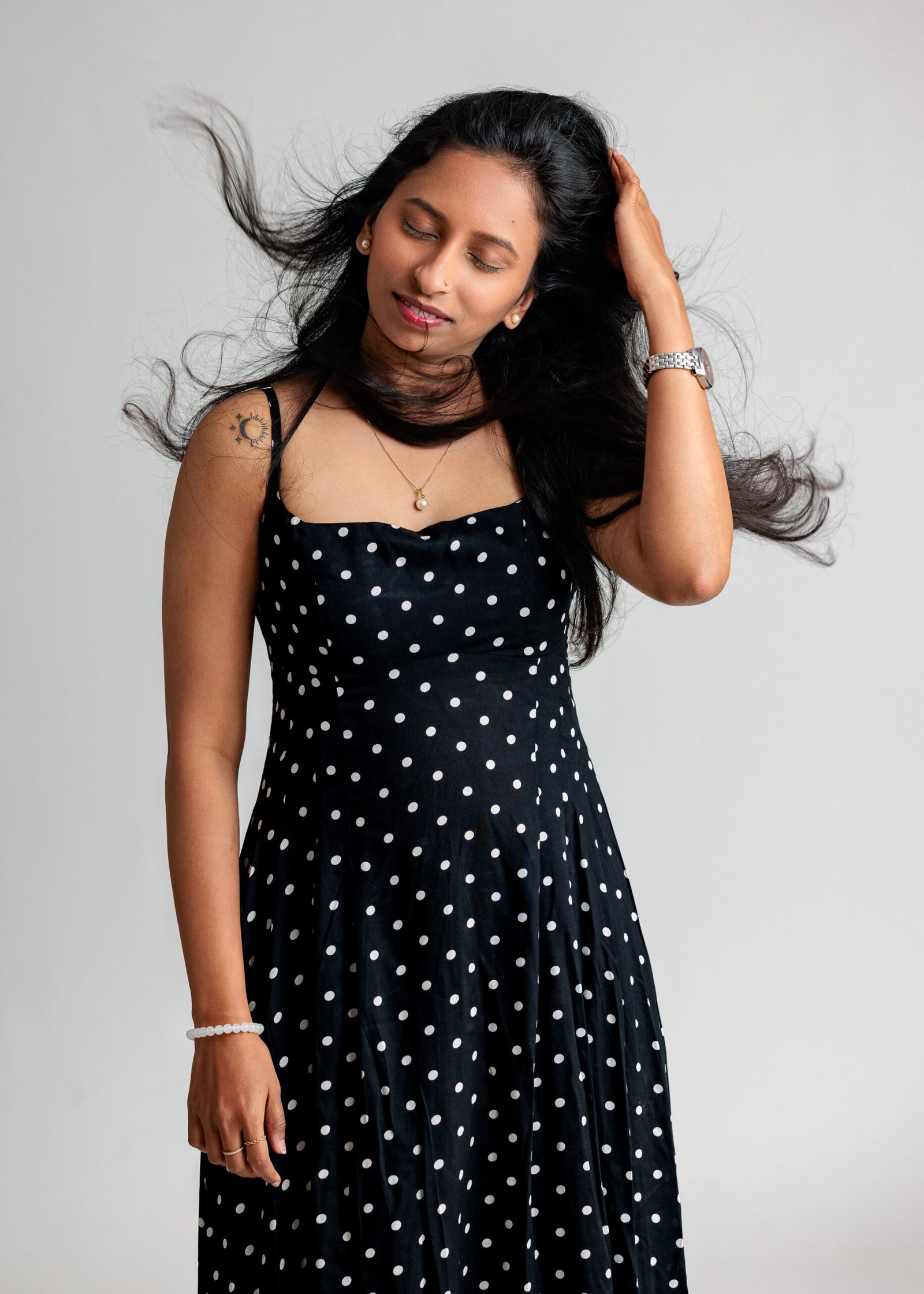 Studio portrait of a woman in a black polka-dot dress with flowing hair