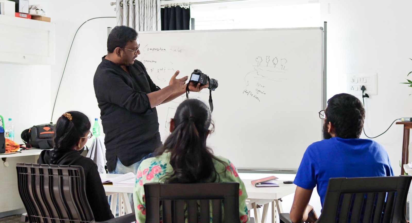 Photography instructor demonstrating a camera to students during a classroom lesson