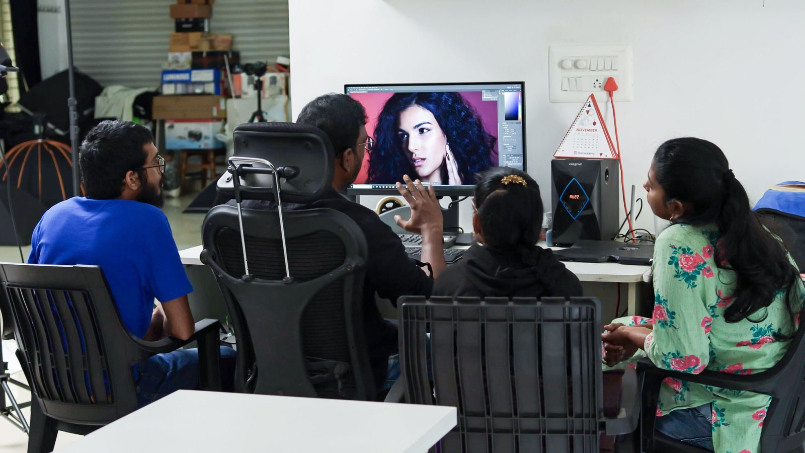 Students learning portrait editing around a desktop monitor