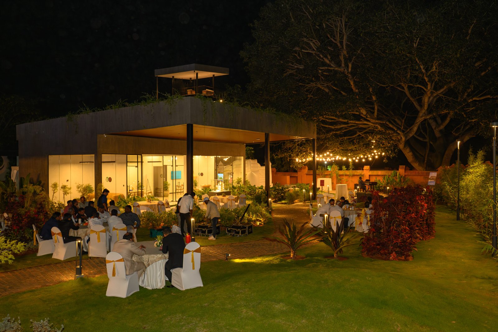 Evening event venue illuminated beside an outdoor lawn