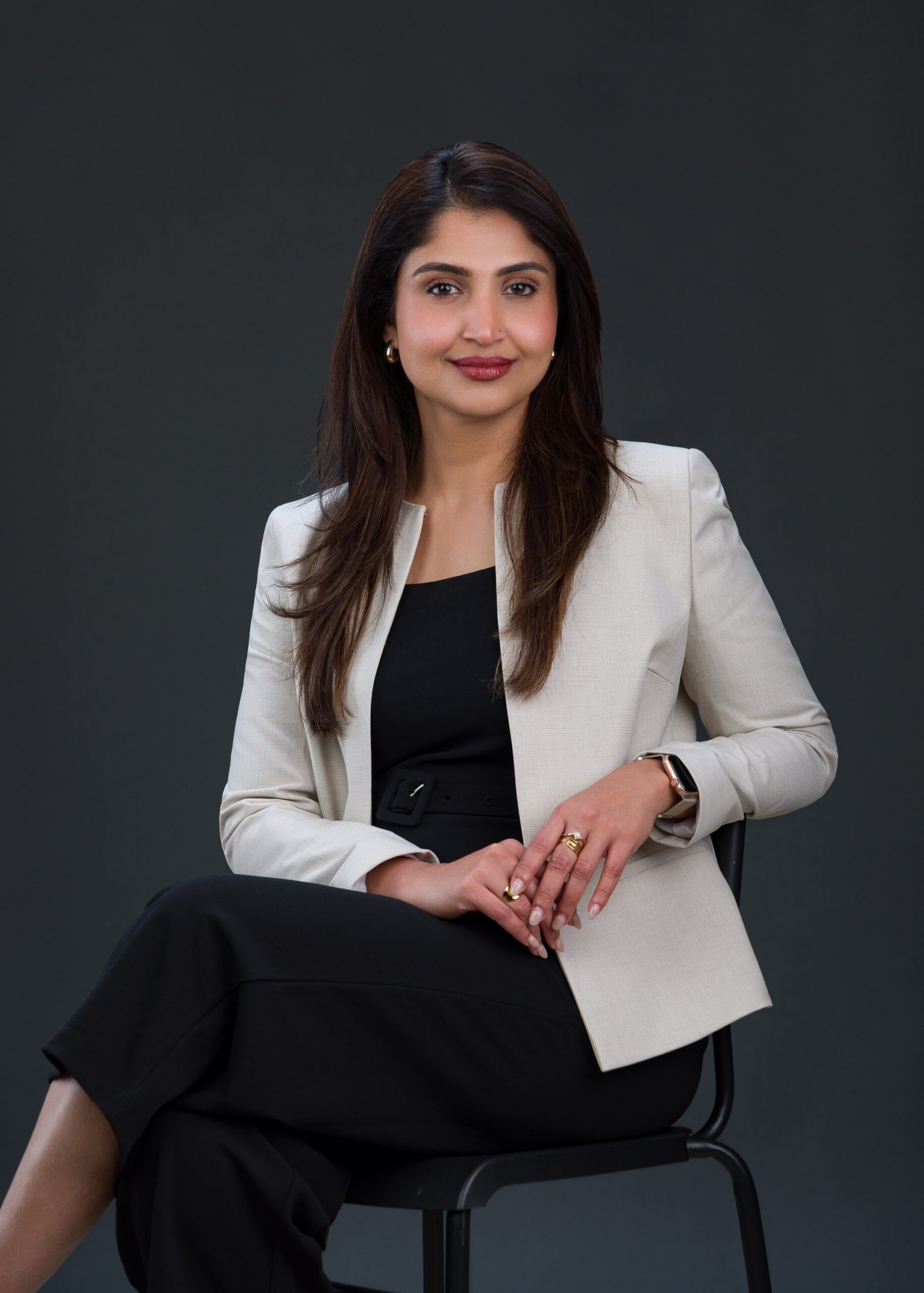 Seated corporate portrait of a woman in a light blazer with her hands clasped
