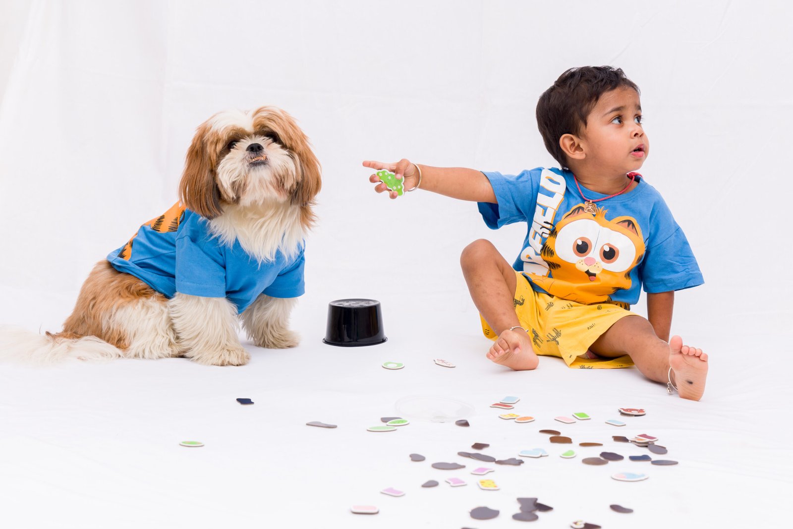 Young boy and family dog sitting among toys in a bright studio