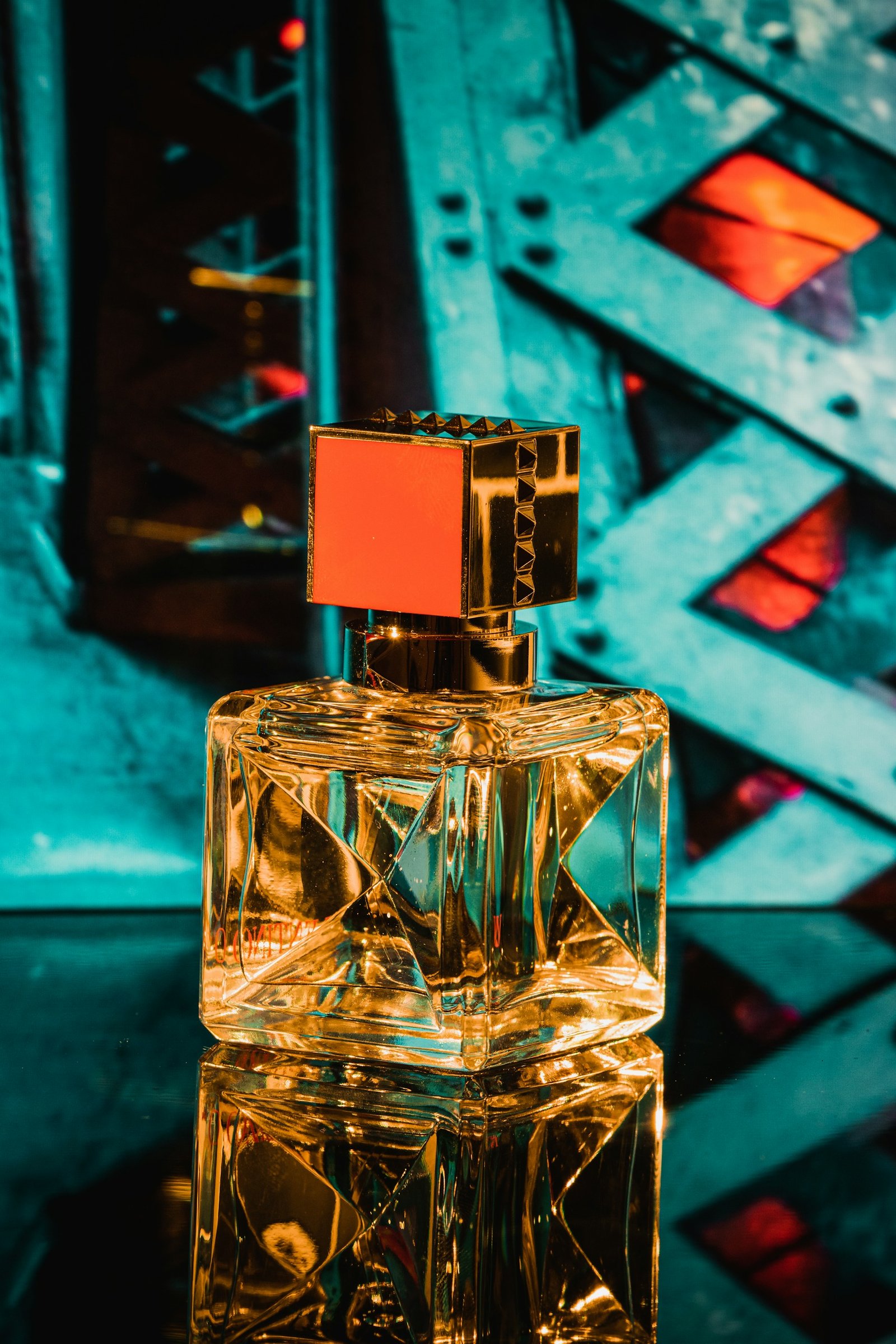 Glass fragrance bottle on a teal background