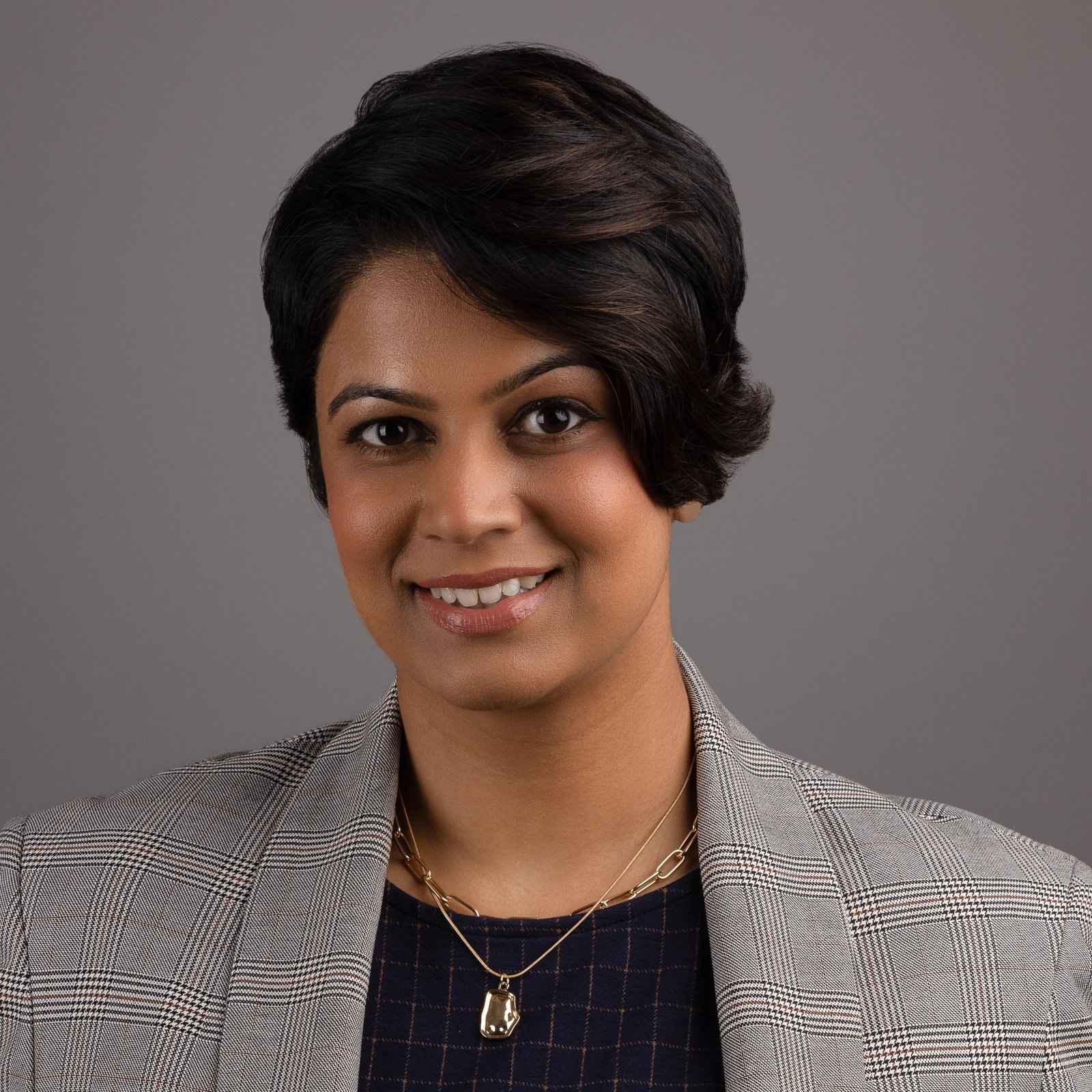 Professional headshot of a woman in a checked blazer