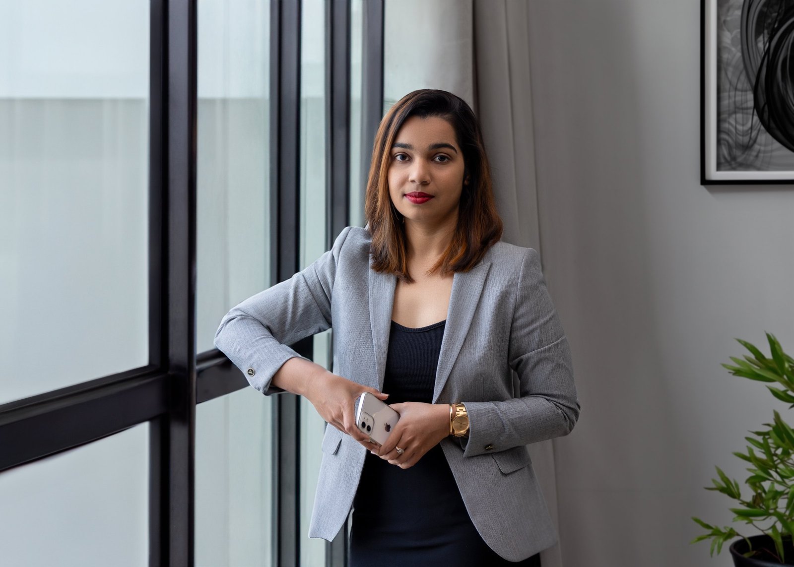 Professional portrait of a woman in a light blazer beside an office window