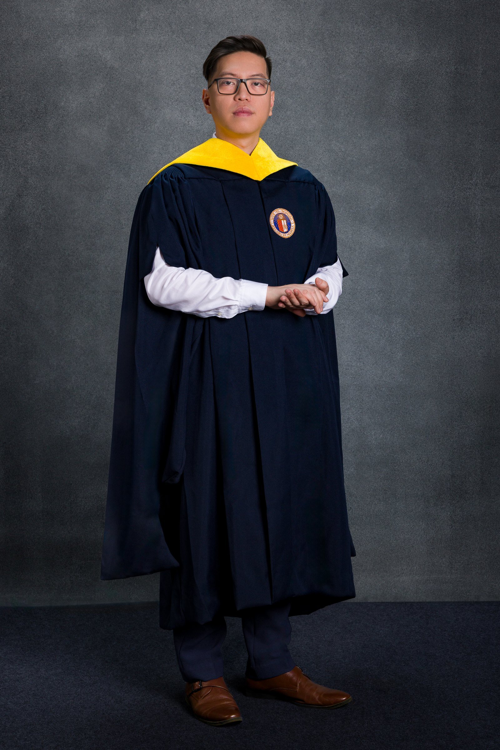 Graduation portrait in a dark gown with a yellow collar