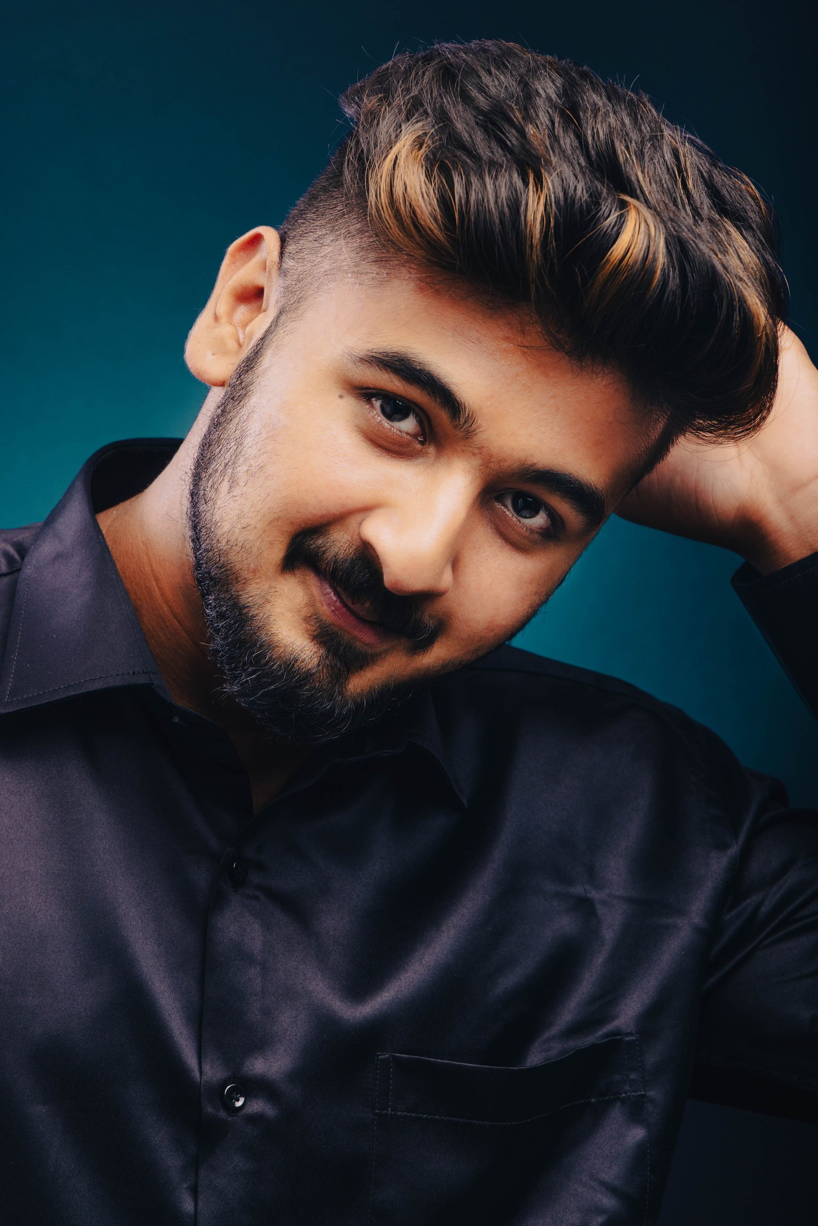 Close studio portrait of a man against a teal background
