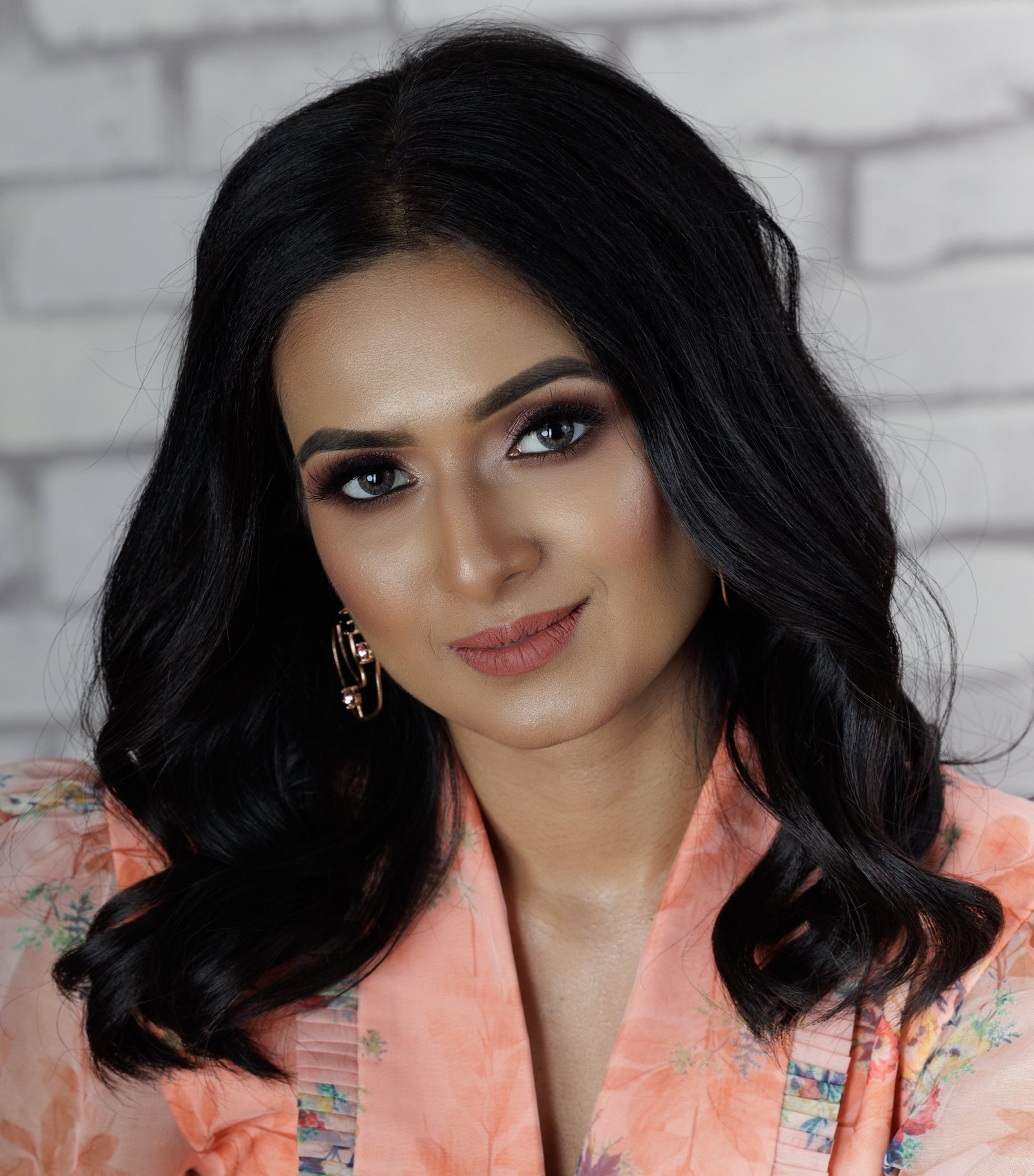 Fashion portrait in a peach outfit against a white brick wall