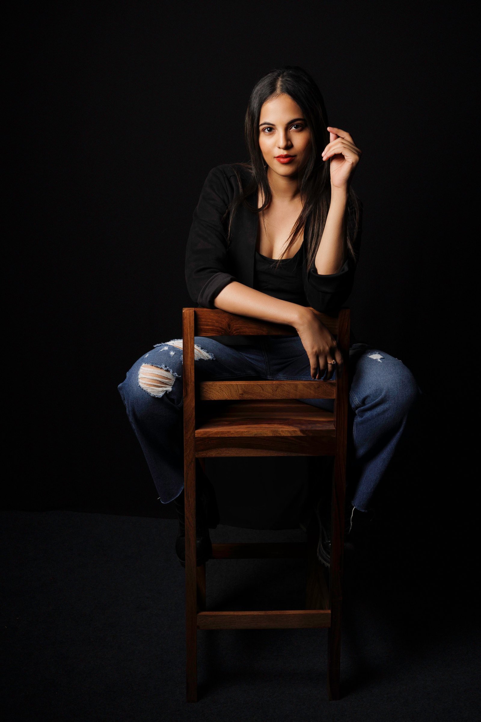 Dramatically lit editorial portrait of a woman seated on a chair