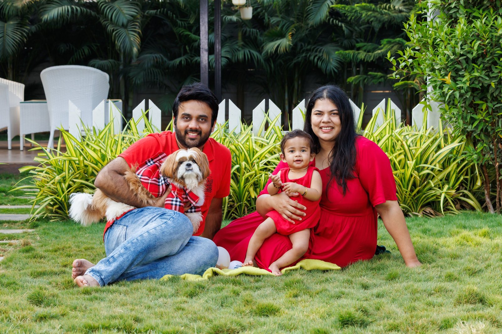 Family with their baby and dog sitting together on a lawn