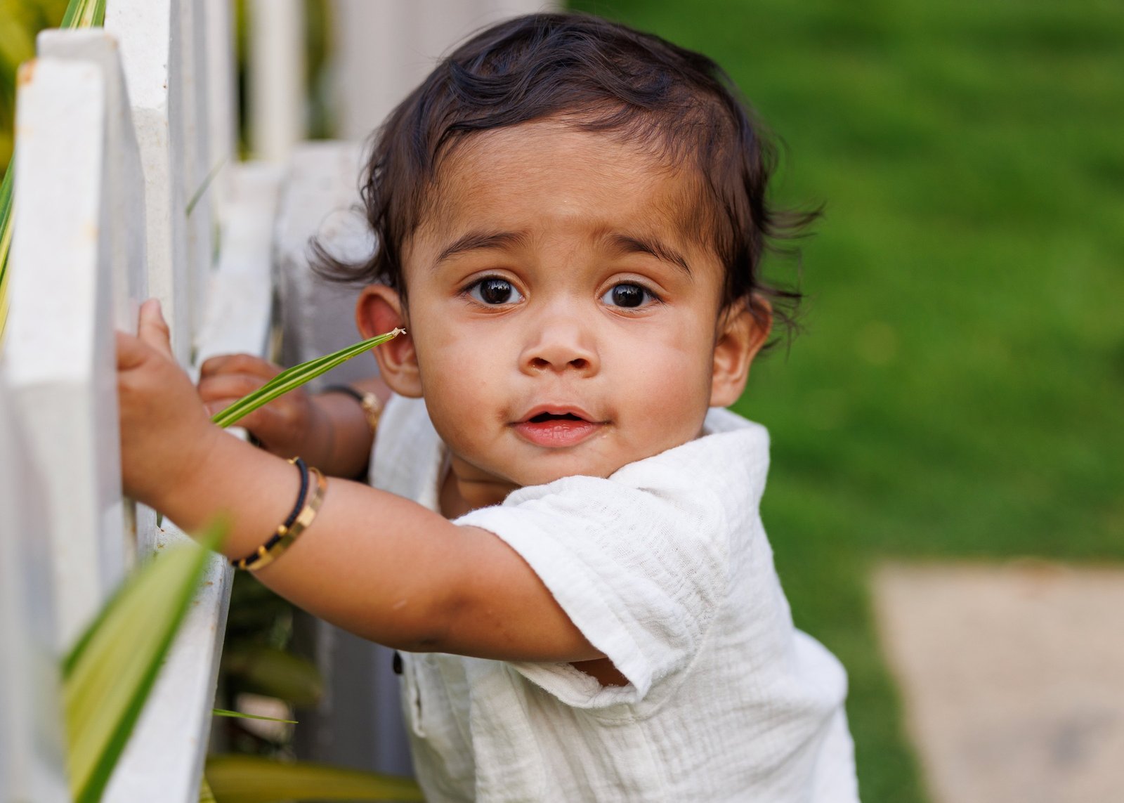 Close portrait of a baby beside a white fence