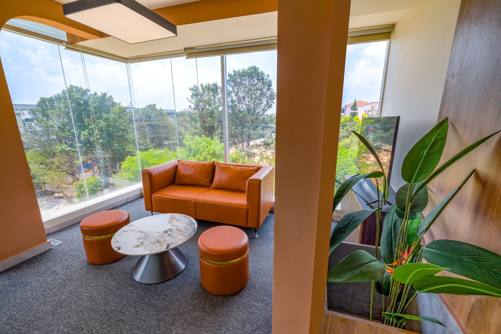 Bright lounge with an orange sofa beside large windows